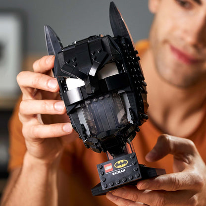 Adult fan showcasing the LEGO® Batman Cowl Set 76182, a detailed black cowl model for collectors.