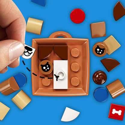 Child assembling LEGO® DOTS dog accessories craft set with colorful tiles on a blue background.