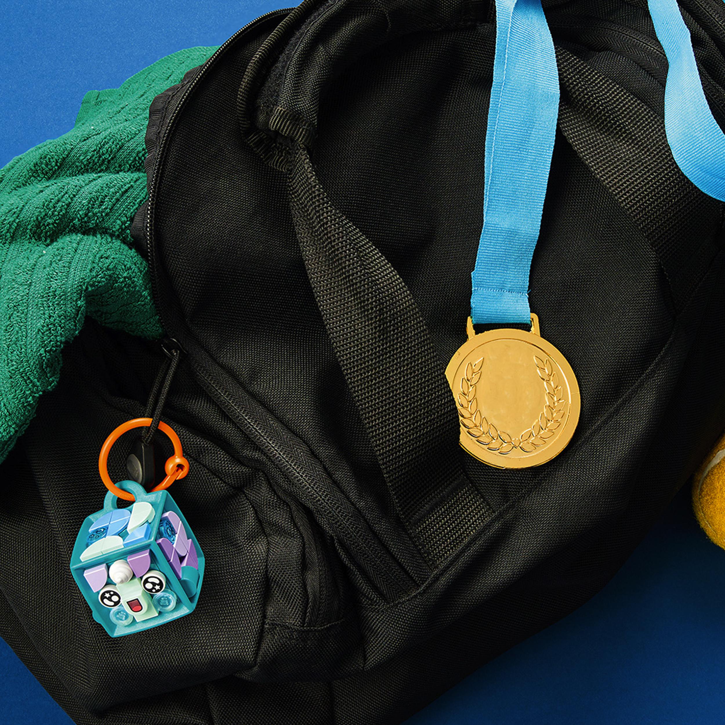 LEGO® DOTS Narwhal bag tag attached to a black backpack, showcasing customizable accessories for kids.