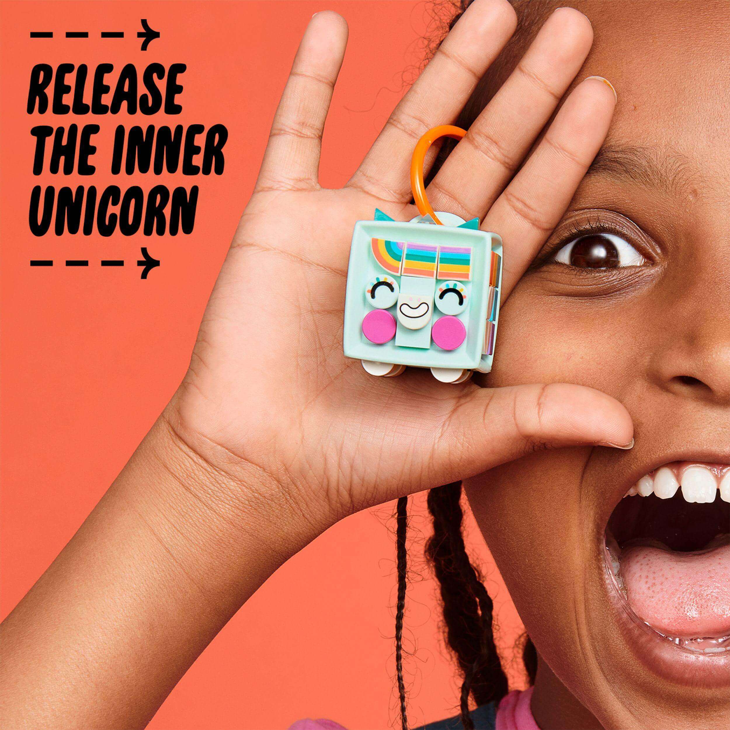 Child holding LEGO® DOTS unicorn bag tag with a big smile, showcasing creativity and fun arts & crafts.
