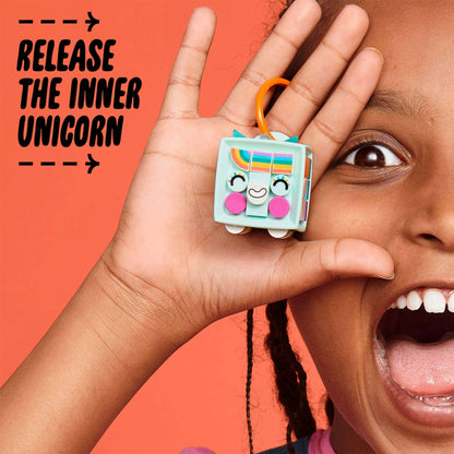 Child holding LEGO® DOTS unicorn bag tag with a big smile, showcasing creativity and fun arts & crafts.