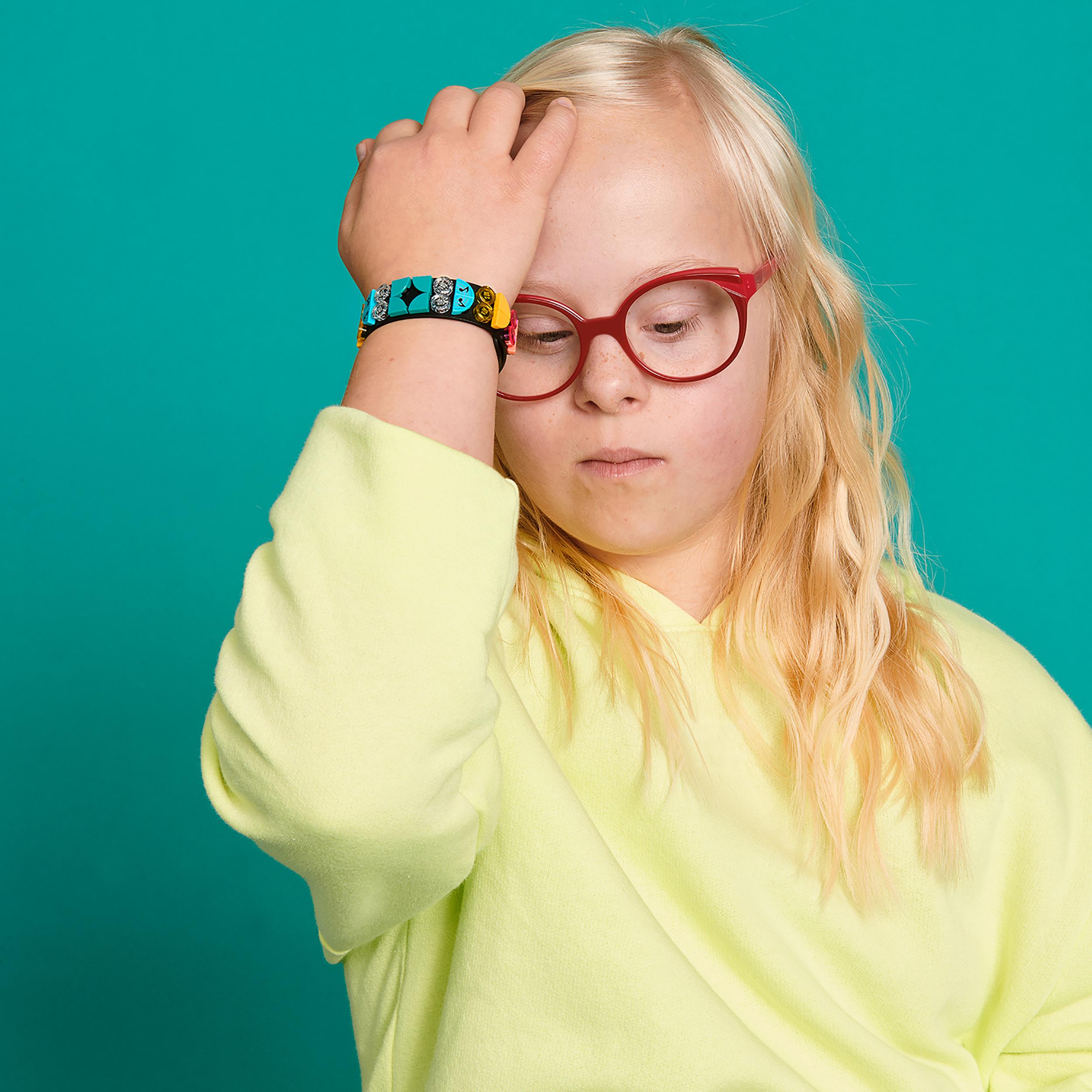 Child wearing a LEGO® DOTS Music Bracelet craft set with colorful tiles, showcasing creativity and fun.