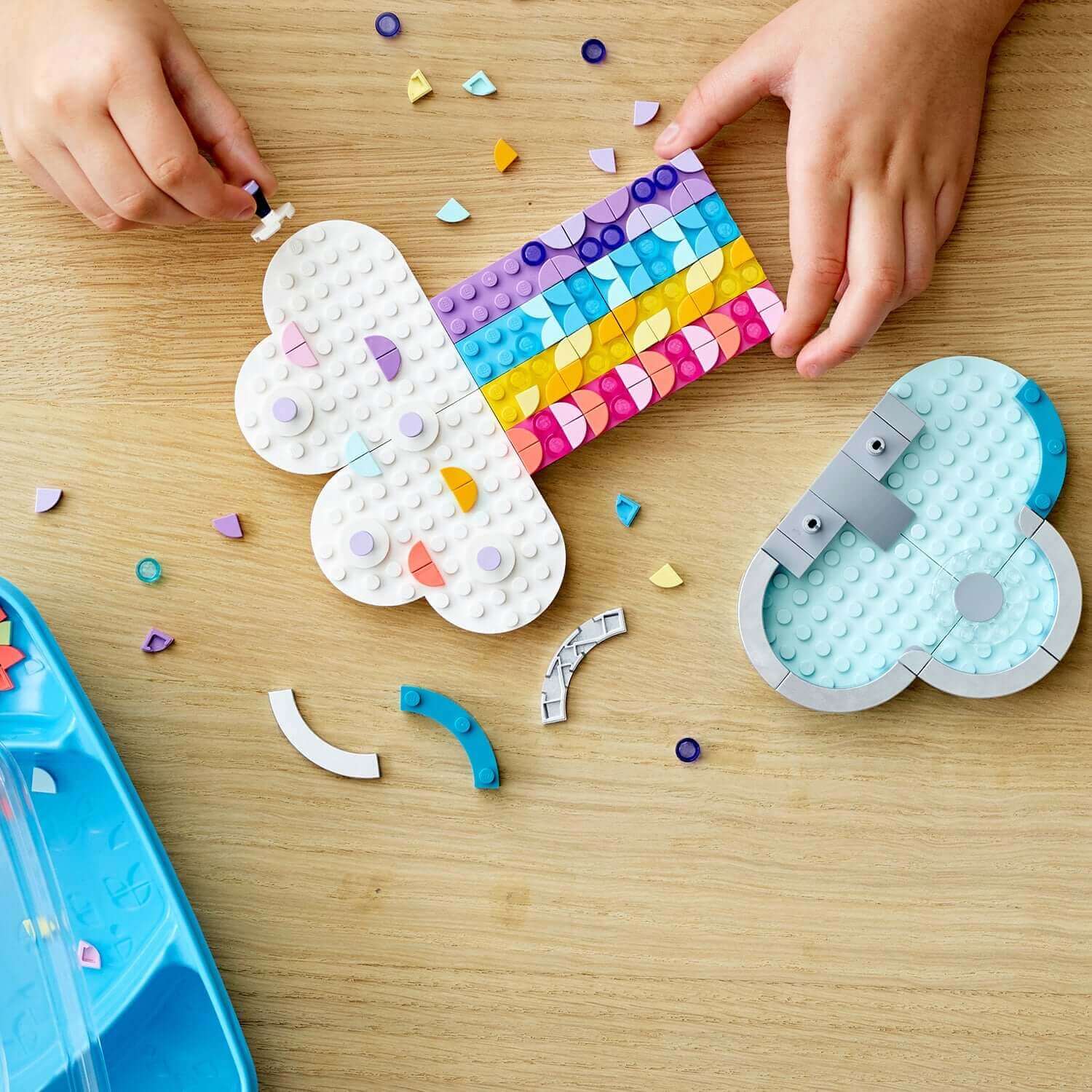 Kids creating the DOTS Rainbow Jewellery Stand Set by LEGO®, featuring colorful cloud and rainbow designs.