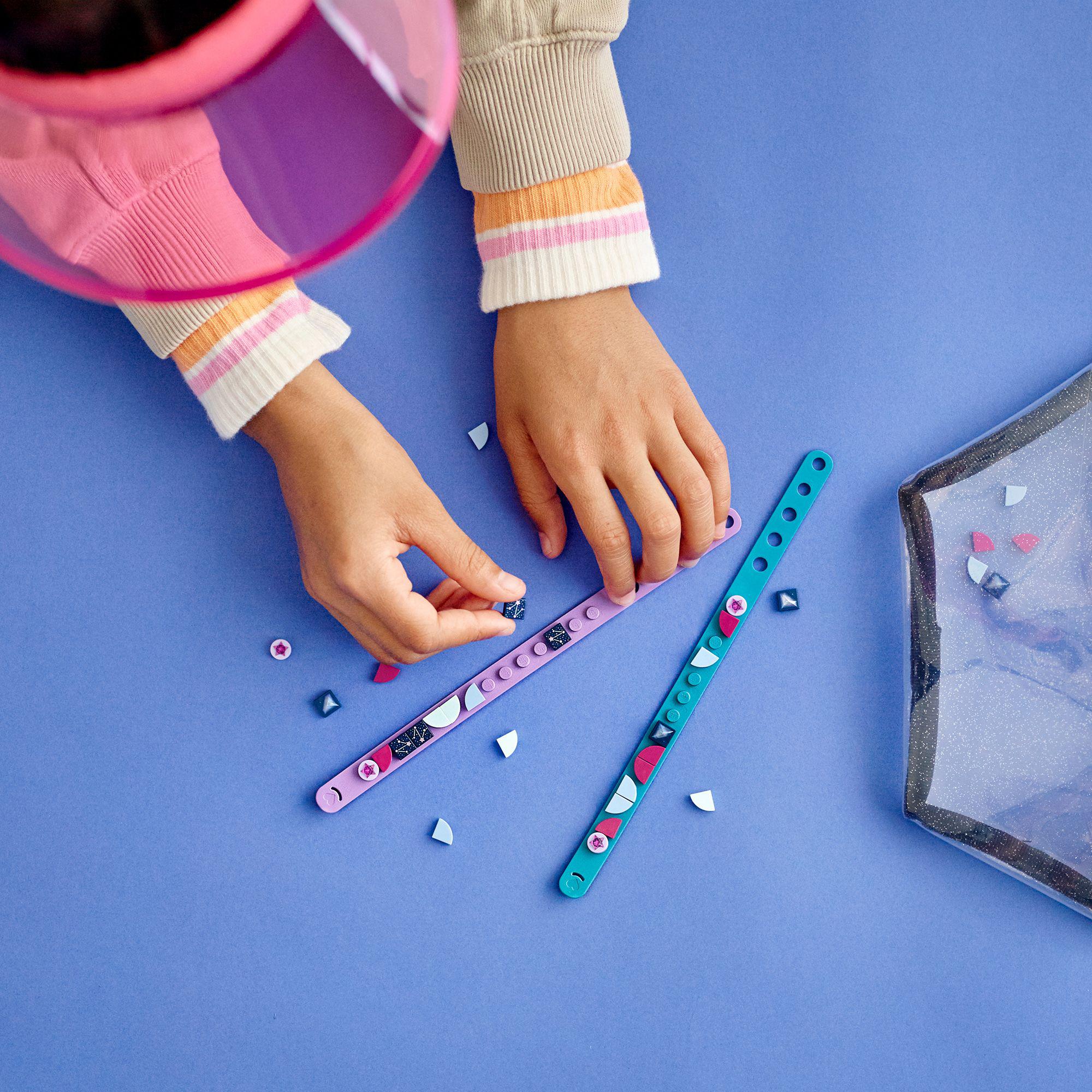 Child creating with LEGO® DOTS starlight bracelets set showcasing teal and purple bracelets with decorative tiles.