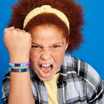 Child showing excitement with LEGO DOTS Starlight Bracelets, featuring teal and purple designs on a vibrant background.