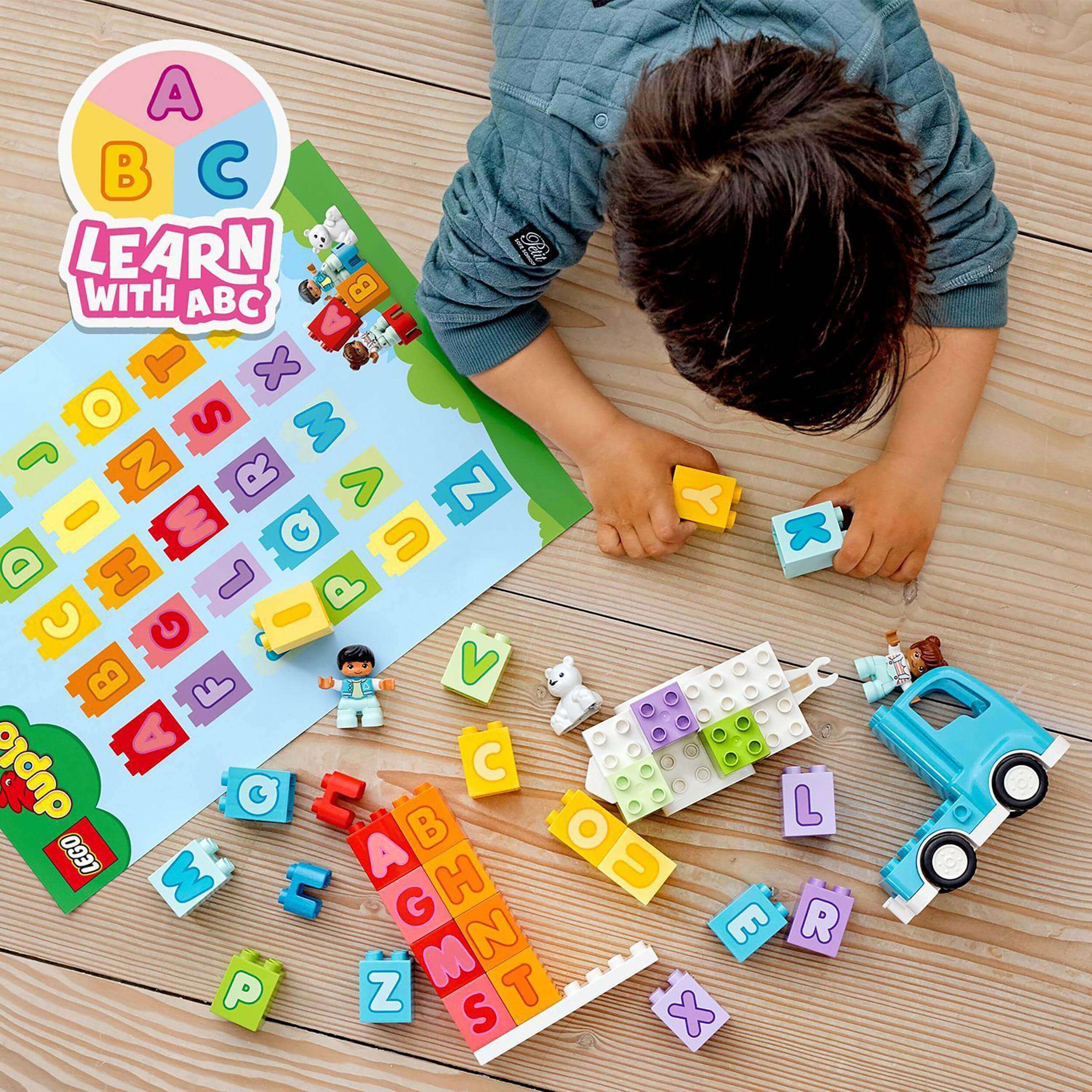 Child playing with LEGO DUPLO Alphabet Truck, learning letters with building blocks and colorful letters for preschool learning.