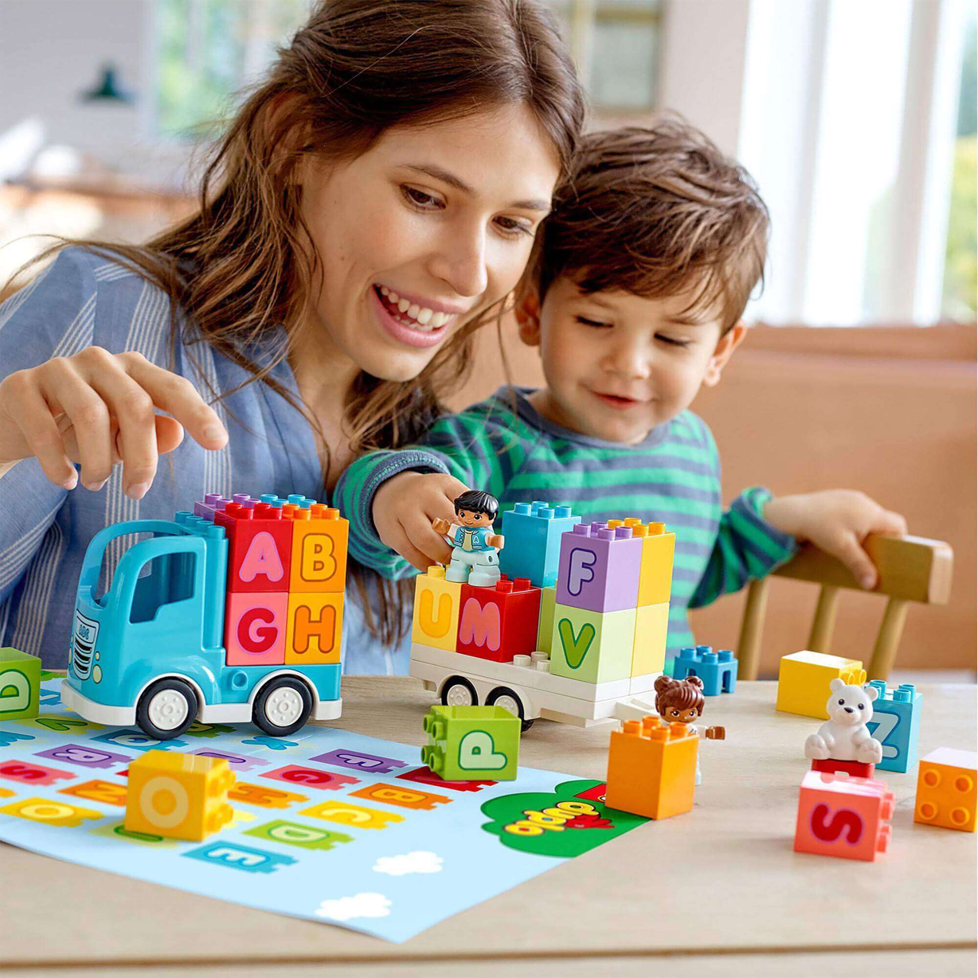 Mother and child playing with LEGO® DUPLO Alphabet Truck set, building letters and having fun together.