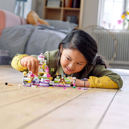 Child enjoying LEGO® Friends Baking Competition Playset 41393 as she decorates colorful LEGO® cakes on the floor.