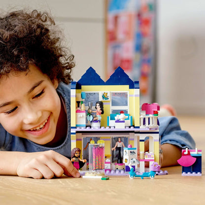 Child enjoying LEGO® Friends Emma's Fashion Shop Play Set 41427, showcasing a vibrant fashion store and studio.
