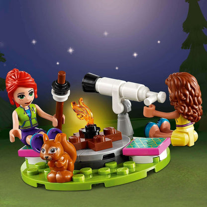 LEGO® Friends Nature Glamping set with two girls by a campfire, telescope, and a squirrel under a starry night.