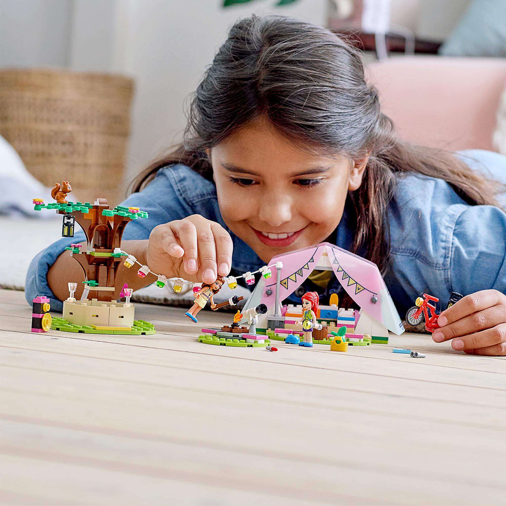 Child enjoying the LEGO® Friends Nature Glamping Camping Set 41392, playing with tent, tree, and friends.