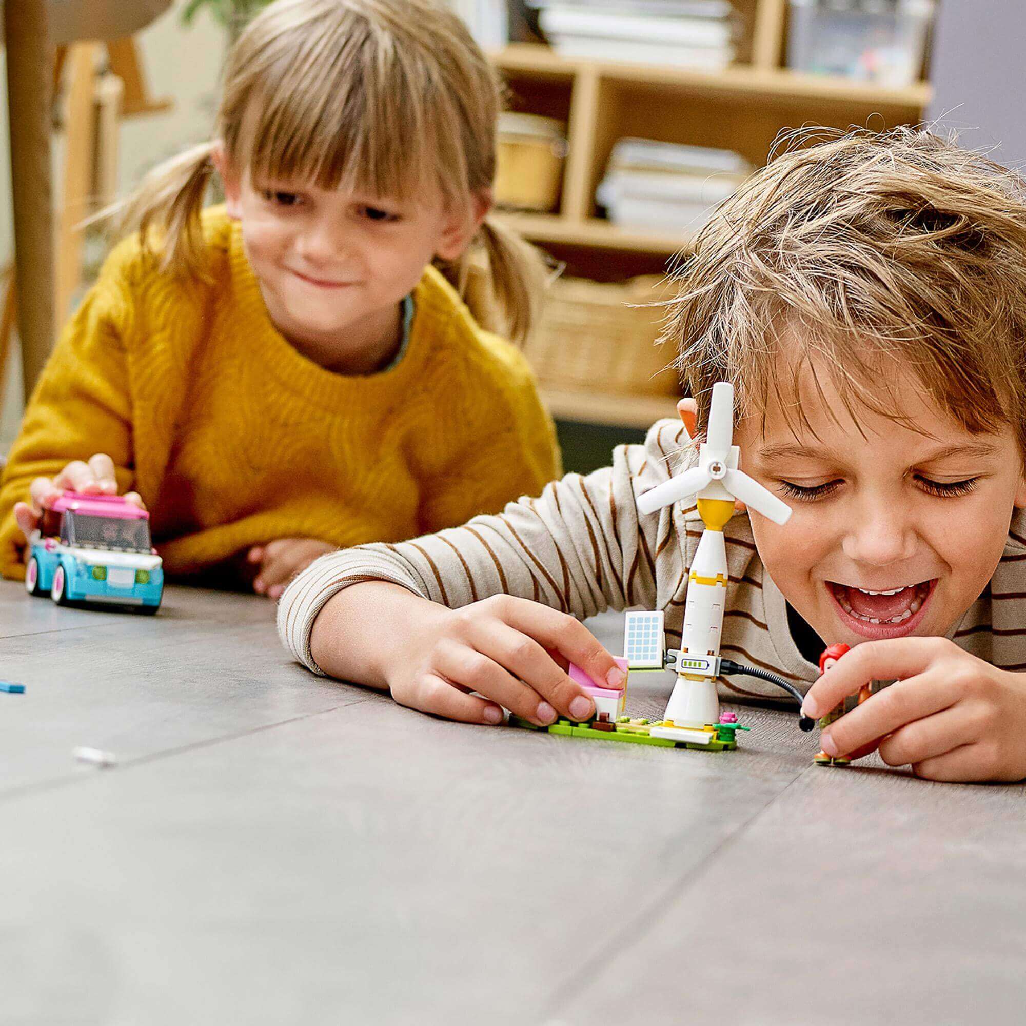 Kids playing with LEGO® Friends Olivia's Electric Car Toy set, featuring a fun electric car and charging station.