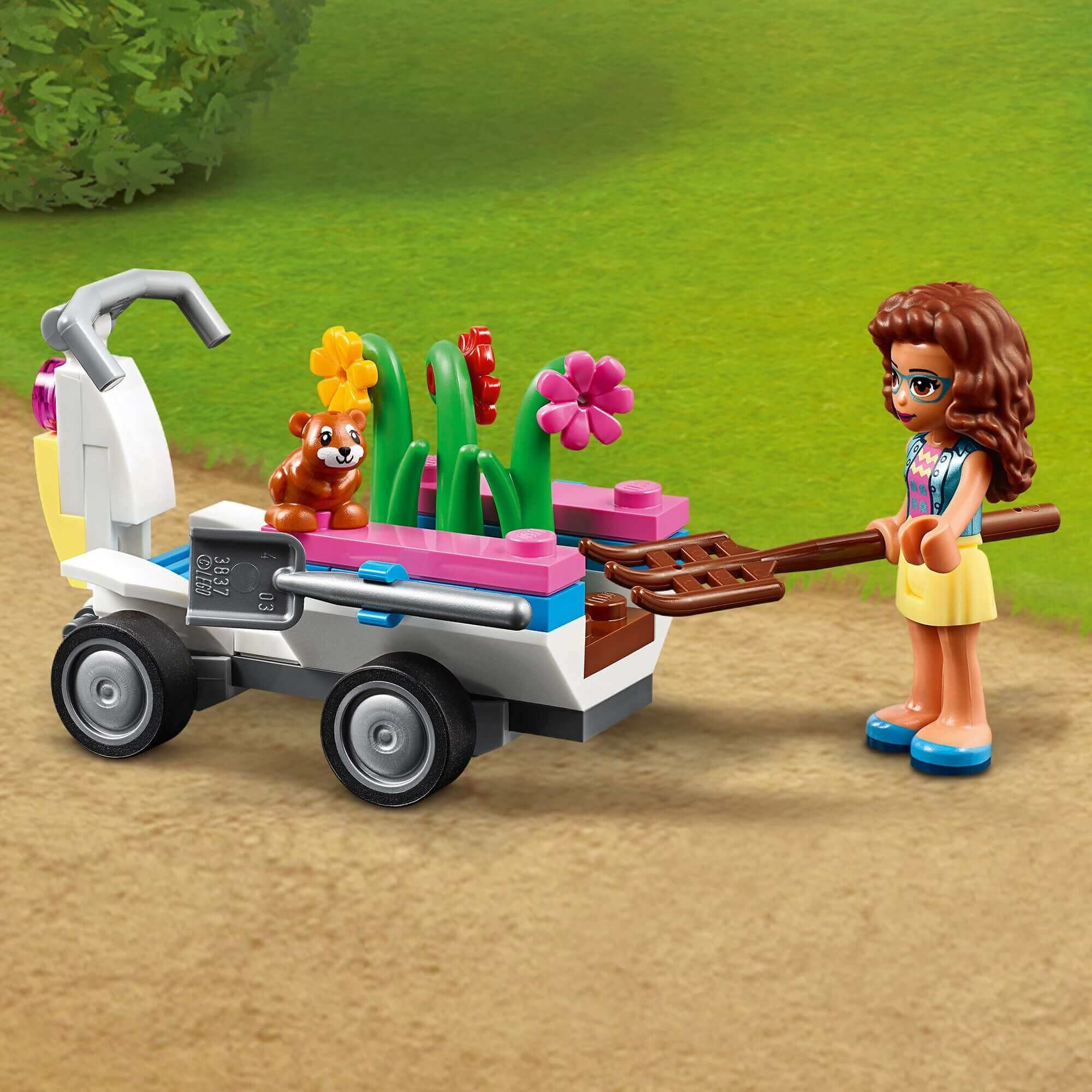 LEGO Friends Olivia with a garden cart full of flowers and a bear, part of Olivia's Flower Garden Play Set 41425.