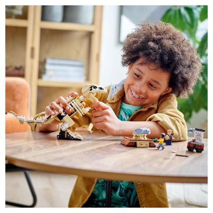 Child playing with LEGO® Jurassic World T. rex dinosaur fossil set, smiling and engaging with toy figures.