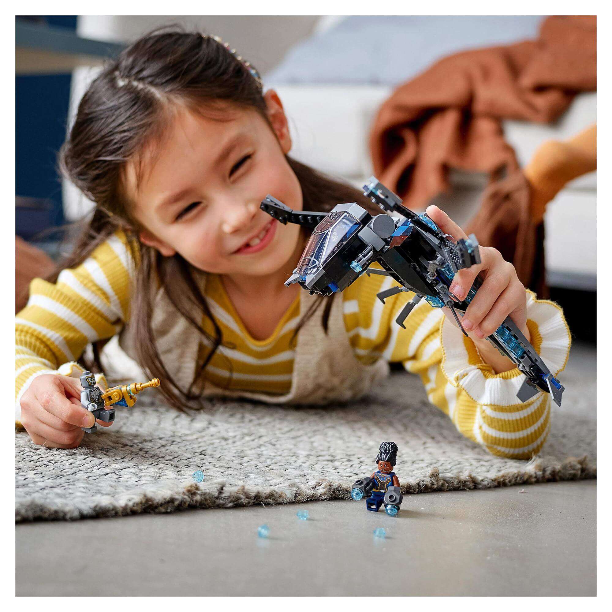 Young girl playing with LEGO® Marvel Black Panther Dragon Flyer set 76186, featuring iconic dragon aircraft and characters.