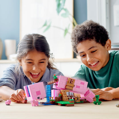 Kids enjoying LEGO® Minecraft The Pig House playset with characters and vibrant pink pig-shaped house.