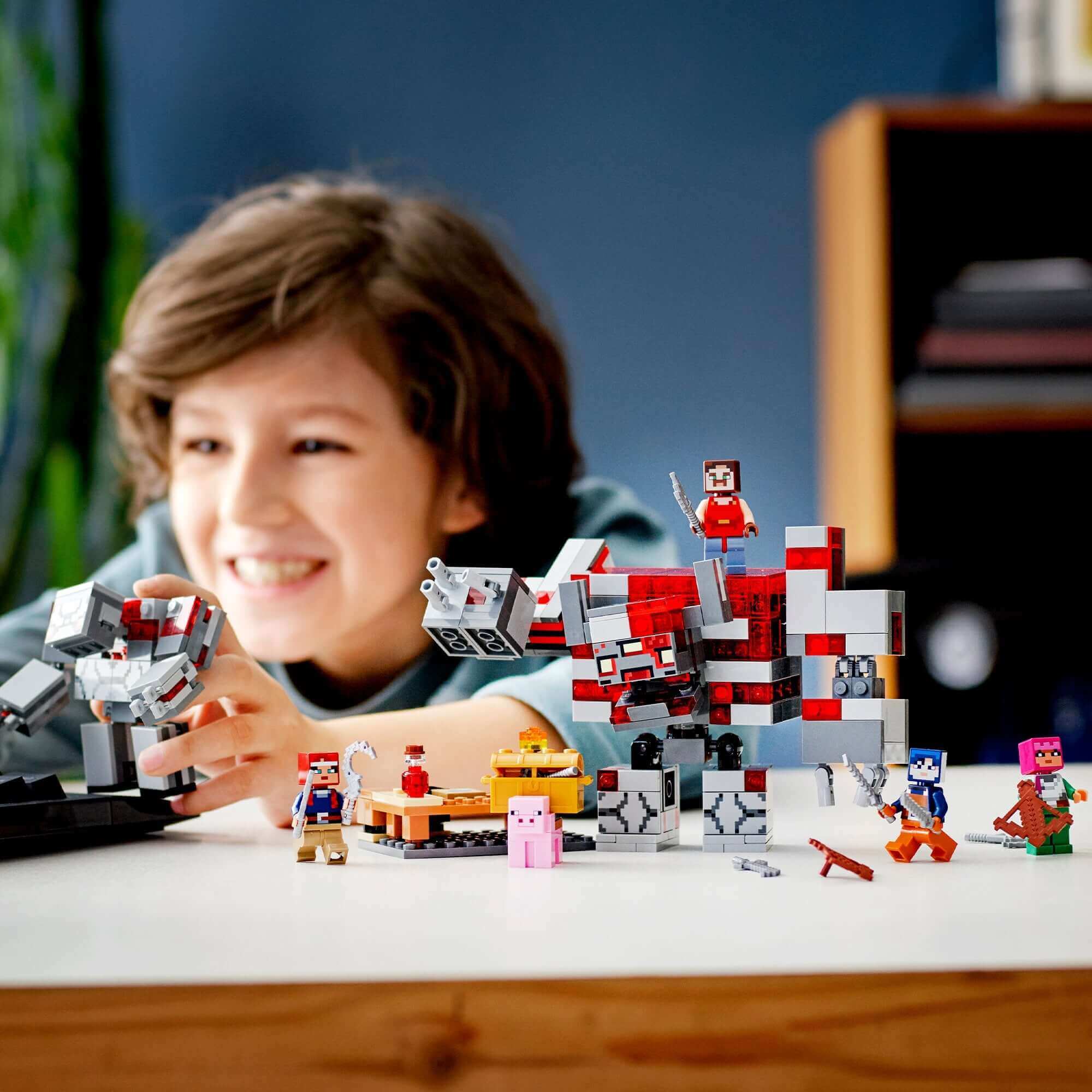 Child building with LEGO Minecraft The Redstone Battle Set 21163, featuring characters and posable giants for role-play adventures.