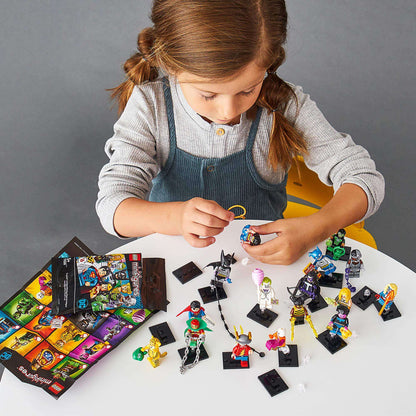 Child playing with LEGO® Minifigures DC Super Heroes Series 71026 at a table, showcasing iconic characters from the DC Universe.