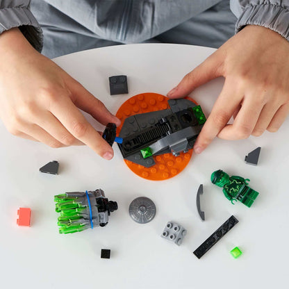 Child assembling LEGO® NINJAGO Spinjitzu Burst - Lloyd Set 70687 with colorful bricks on a table.