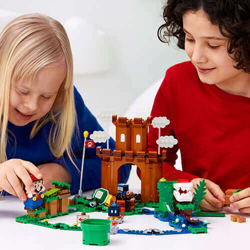 Kids playing with LEGO® Super Mario™ Guarded Fortress Set 71362, featuring a fortress, characters, and interactive elements.