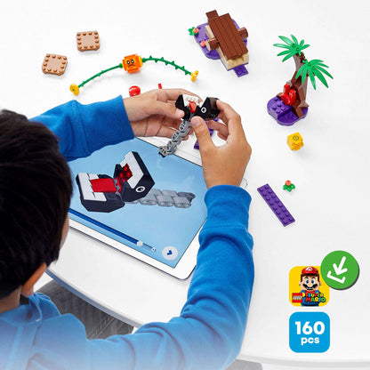 Child playing with LEGO® Super Mario Jungle Encounter Expansion Set 71381 on a tablet, surrounded by colorful building pieces.