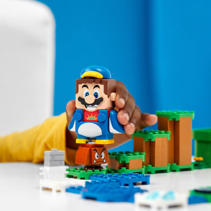 Child holding LEGO® Super Mario Penguin Mario figure in an interactive play scene with blocks and obstacles.