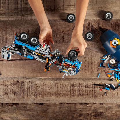Child assembling a LEGO® Technic Concrete Mixer Truck Toy with colorful building blocks and wheels on a wooden table.