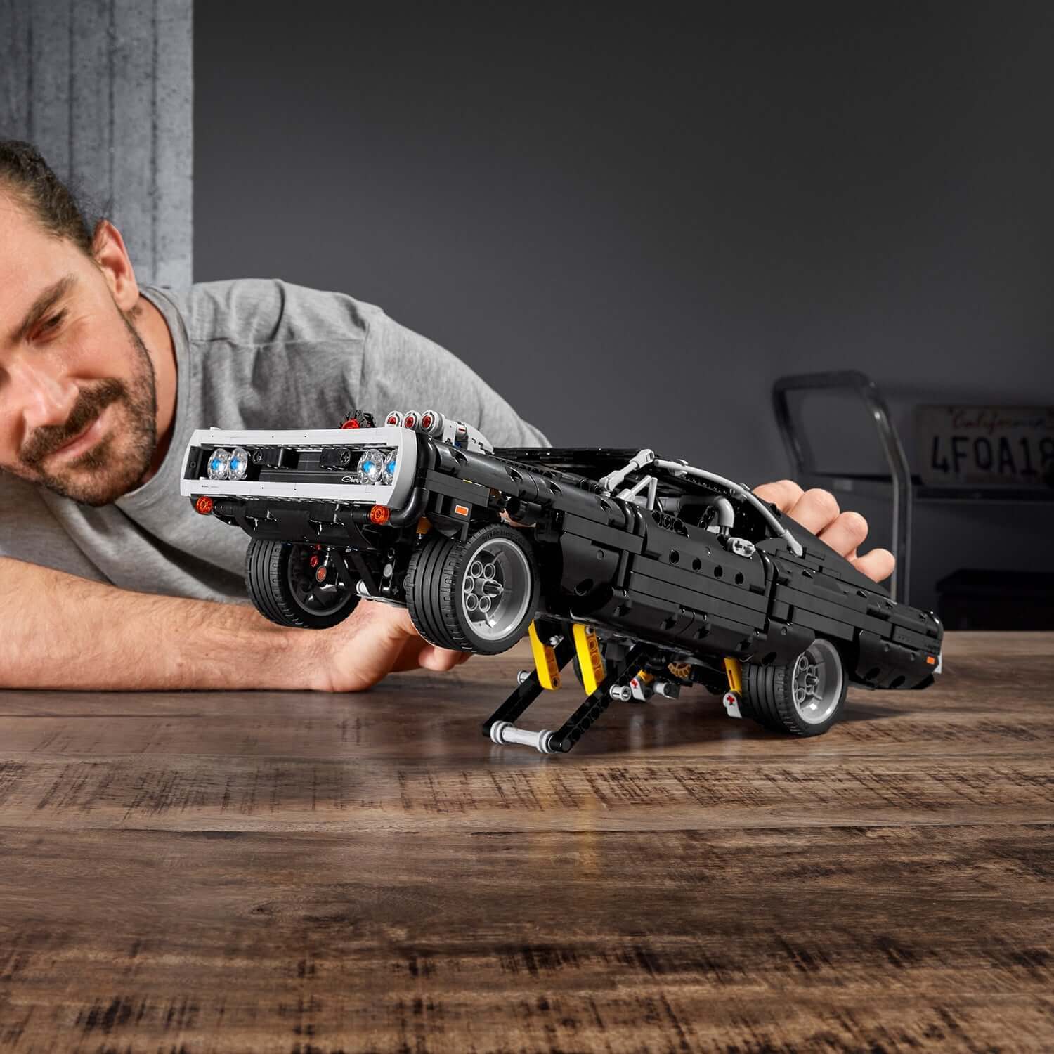 LEGO Technic Dom's Dodge Charger set 42111 being showcased by a man, highlighting cool stunts from The Fast and The Furious.