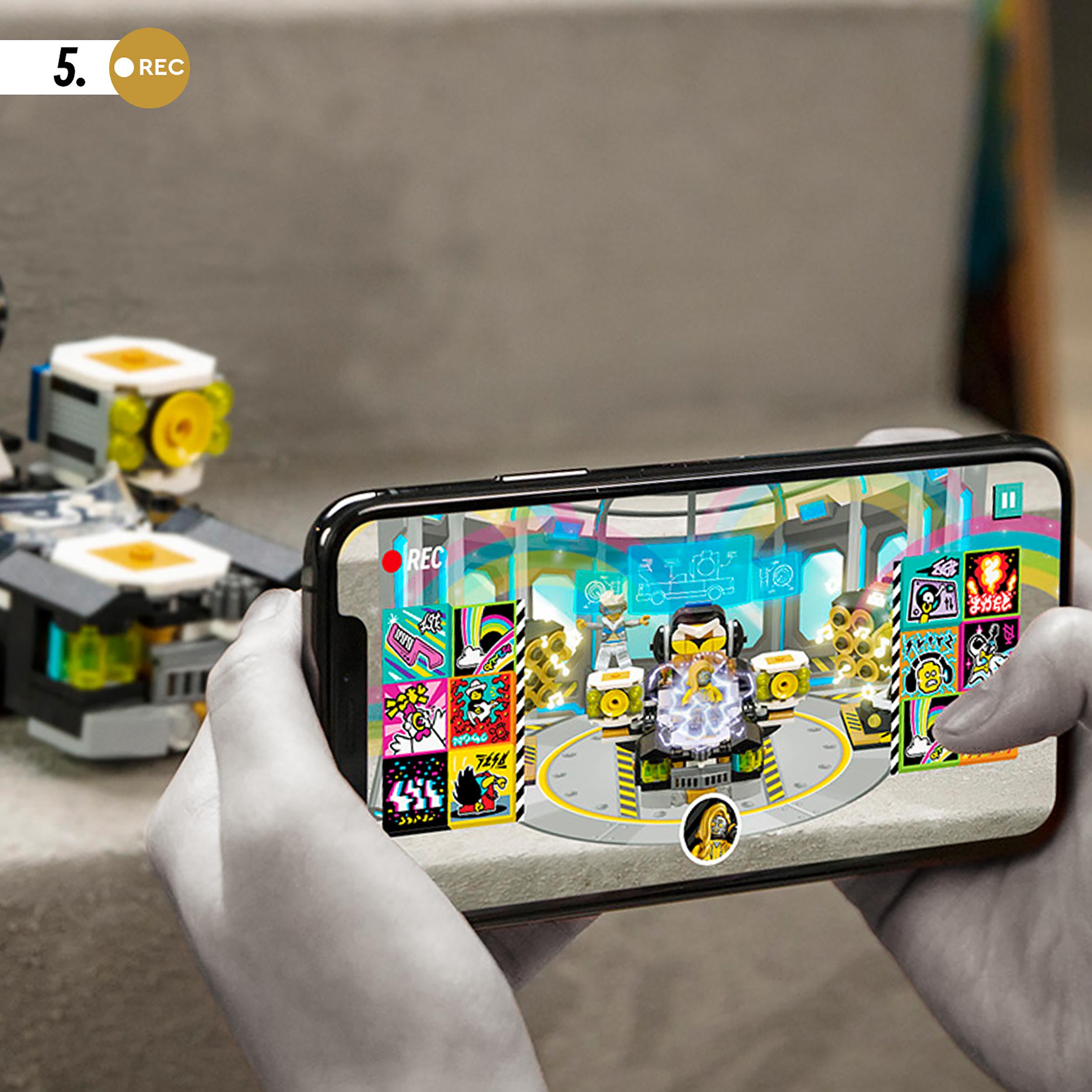Child using smartphone to create music video with LEGO® VIDIYO Robo HipHop Car set, colorful app interface visible.
