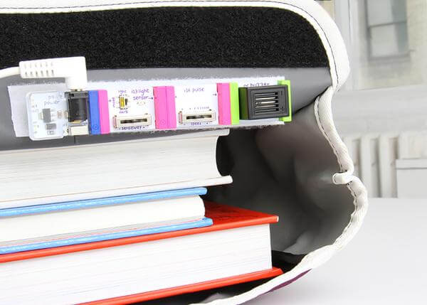 Electronics components from the littleBits STEAM Student Set integrated with stacked books for creative learning.