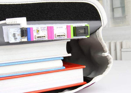 Electronics components from the littleBits STEAM Student Set integrated with stacked books for creative learning.