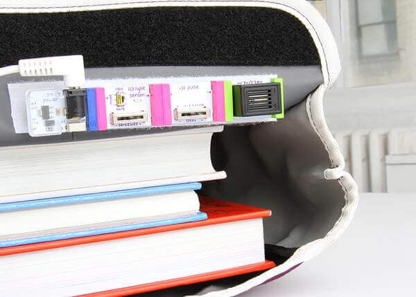 Electronics components from the littleBits STEAM Student Set integrated with stacked books for creative learning.