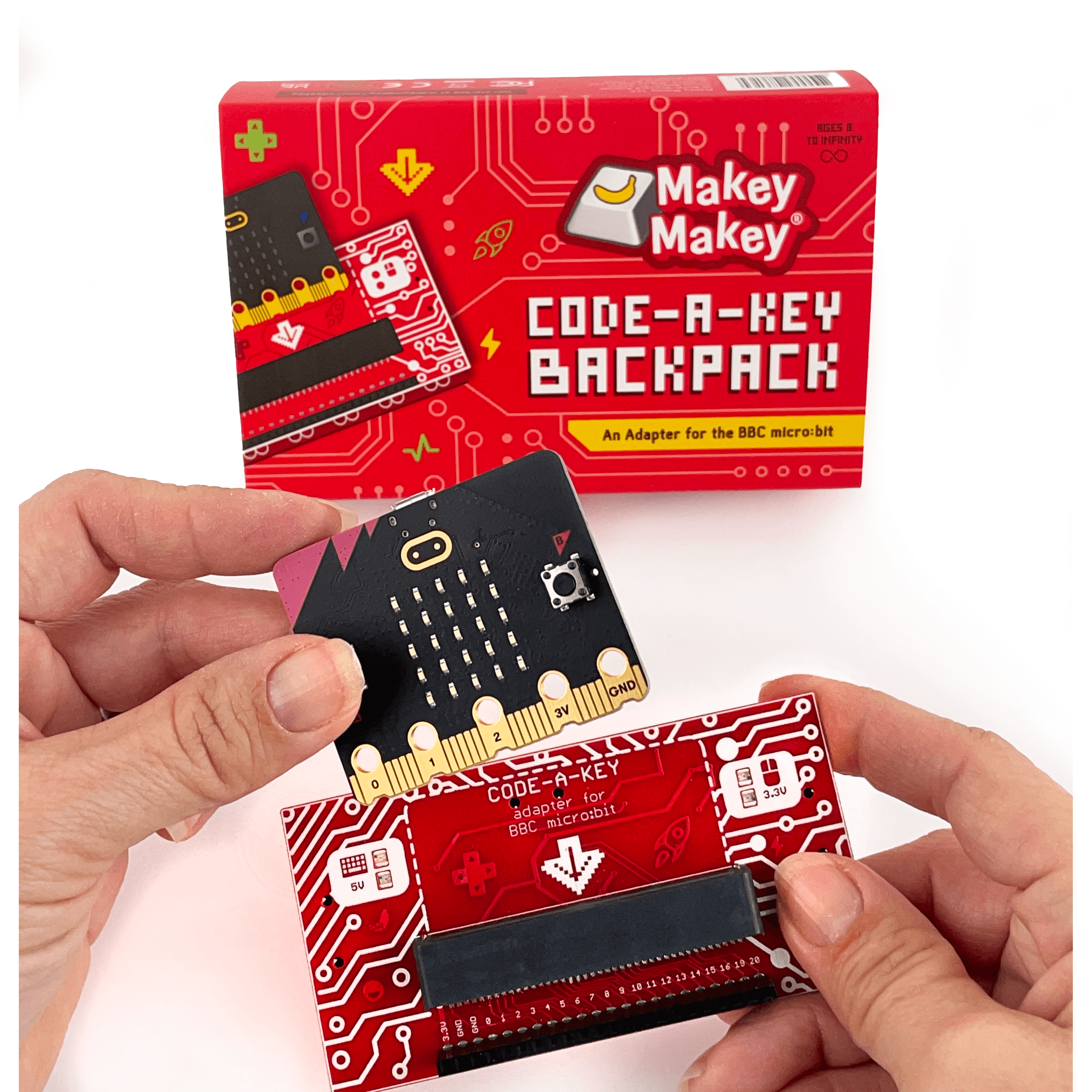 Makey Makey Code-a-Key Backpack adapter being held, designed for BBC micro:bit projects with colorful circuit graphics.