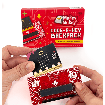 Makey Makey Code-a-Key Backpack adapter being held, designed for BBC micro:bit projects with colorful circuit graphics.