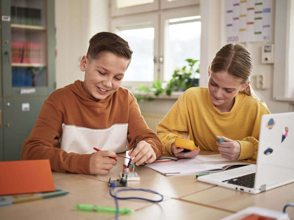 Two middle school students engaged in hands-on learning with an Arduino Education Starter Set in a classroom setting.