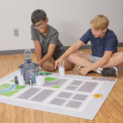 Two boys engaging with the Seeker robot on a coding mat, exploring STEM education through robotics.