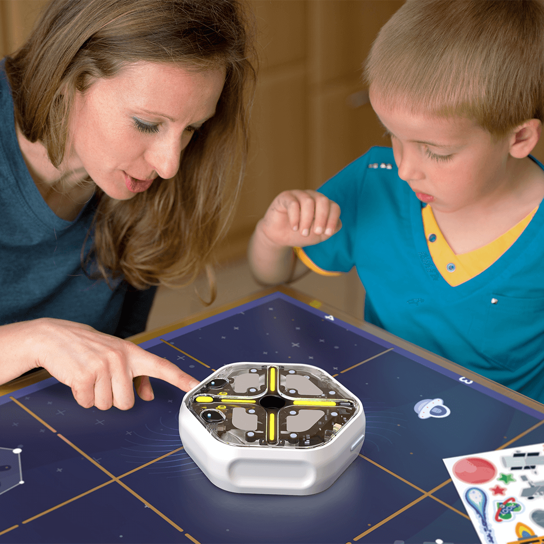 Adult and child exploring coding with Root robot on a space-themed learning table.