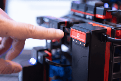 Close-up of a hand pressing the power button on a robotics kit from the Sphero Blueprint Engineering Class Pack.