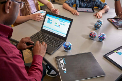 Student programming Sphero BOLT+ robots at a table, showcasing hands-on coding education experience.