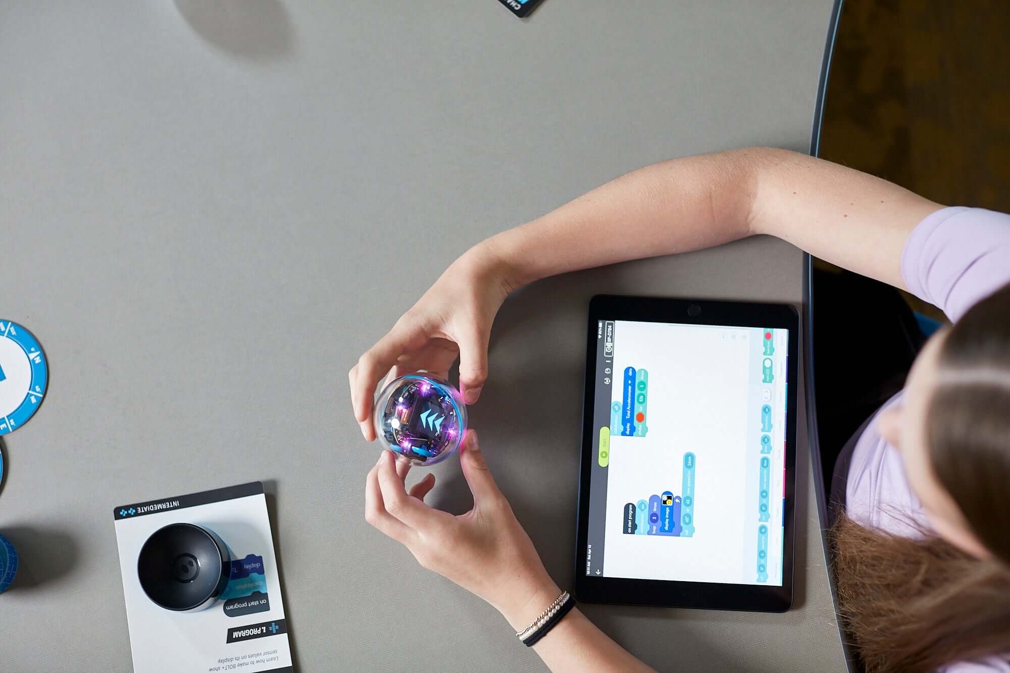 A student programming the Sphero BOLT+ robot using a tablet in a classroom setting.