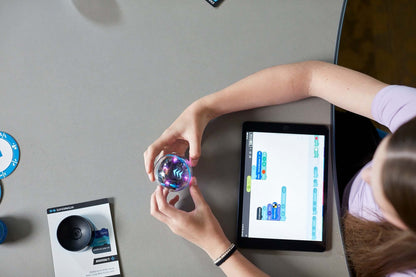 A student programming the Sphero BOLT+ robot using a tablet in a classroom setting.