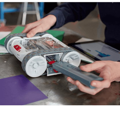 User interacting with Sphero RVR+, plugging in a component on a workbench.