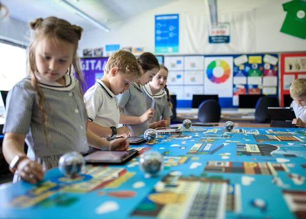 Students engaged in interactive learning activities with tablets and educational tools in a classroom.