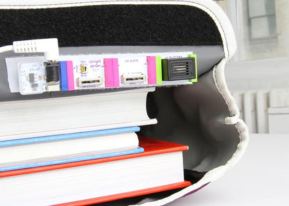 LittleBits STEAM kit with colorful modules alongside stacked books for hands-on learning and engineering.
