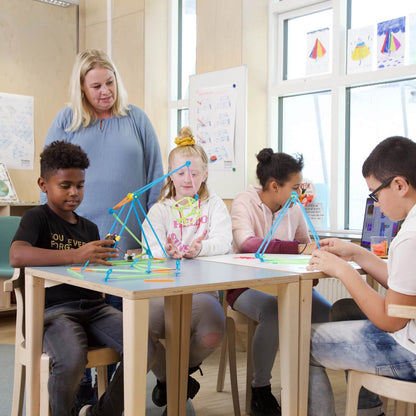 Children engaging with STEAM projects using Strawbees in a classroom setting with a teacher guiding them.
