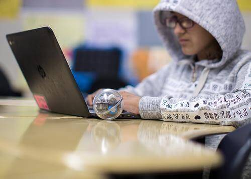 Student programming with Sphero robot on laptop in classroom, focusing on computer science foundations.